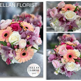 Low round bouquet of pink and peach blooms with white roses in a clear glass vase