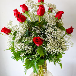 Red roses arranged with white baby's breath in a clear glass vase