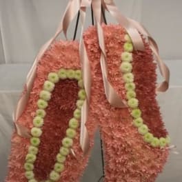 Pink floral standing spray with pale ribbon and green accents