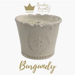 White decorative candle in a ceramic container with gold branding