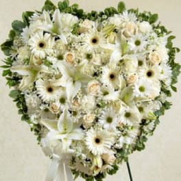 Heart-shaped white floral spray with lilies, daisies, and roses