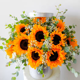 Bouquet of bright sunflowers with white filler flowers in a silver vase