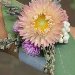 Small boutonniere with a pale peach flower and purple accents