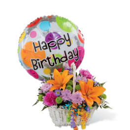 Birthday balloon with bright orange lilies and mixed flowers in a white basket