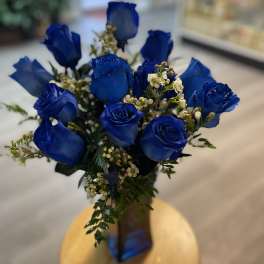 Bouquet of blue roses with small white filler flowers in a vase