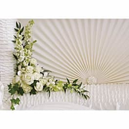 White floral arrangement with roses and orchids on a fan-shaped backdrop