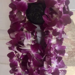 Purple orchid lei draped over a dark doorknob