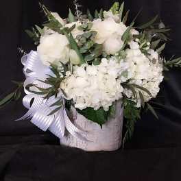 White floral arrangement in a birch-style container with a ribbon bow
