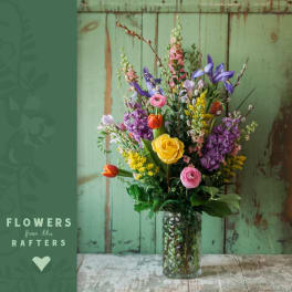 Mixed bouquet in a glass vase with yellow, pink, purple, and orange flowers