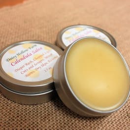 Three tins of calendula salve on burlap fabric