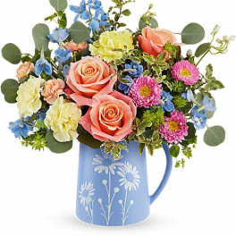 Mixed bouquet of roses, carnations, and daisies in a blue pitcher vase