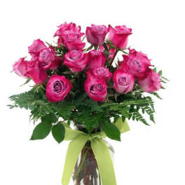 Pink roses arranged in a clear glass vase with a green ribbon