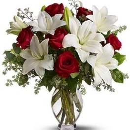 Bouquet of red roses and white lilies in a clear glass vase