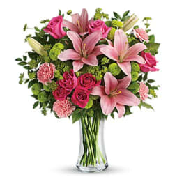 Pink lilies and roses arranged in a clear glass vase