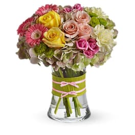 Mixed bouquet of roses, gerbera daisies, and hydrangeas in a glass vase