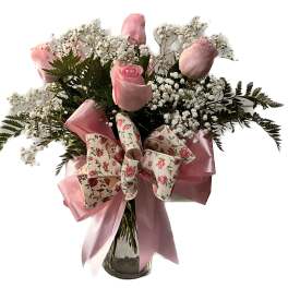 Pink roses in a glass vase with baby's breath and a floral bow