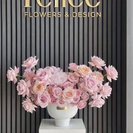 Pink rose arrangement in a white vase on a pedestal