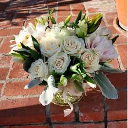 Low glass vase of white roses and pale blooms arranged in a rounded cluster