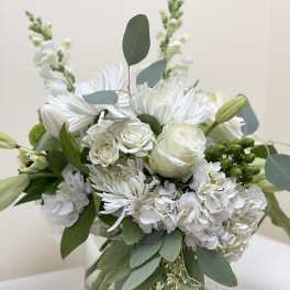 White floral bouquet in a clear glass vase with eucalyptus