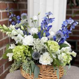 Basket arrangement of blue, white, and green flowers