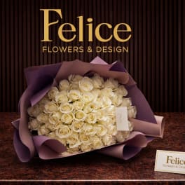 Large bouquet of cream roses wrapped in purple paper