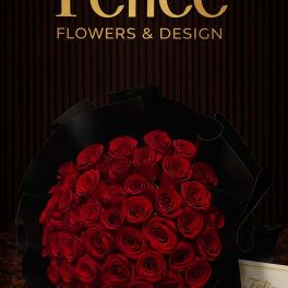 A large bouquet of red roses wrapped in black paper.