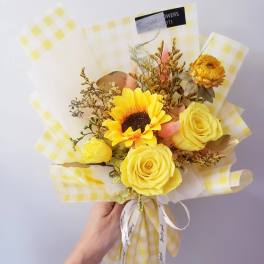 Yellow rose and sunflower bouquet wrapped in checkered paper