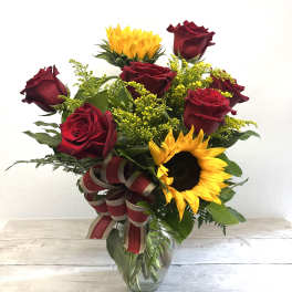 Bouquet of red roses and sunflowers in a glass vase with a ribbon