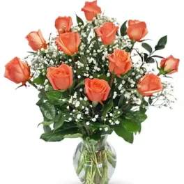 Orange roses arranged in a clear glass vase with baby's breath