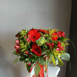 Red rose and gerbera bouquet in a glass vase with ribbon