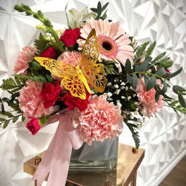 Pink and red mixed bouquet in a glass vase with a butterfly decoration