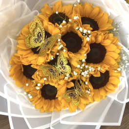 Bouquet of sunflowers wrapped in white paper with gold butterfly accents
