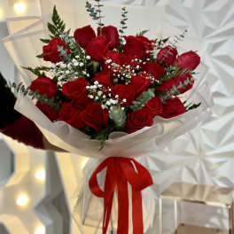 Bouquet of red roses wrapped in white paper with a red ribbon