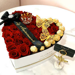 Heart-shaped box of red roses with gold-wrapped chocolates and butterfly decorations
