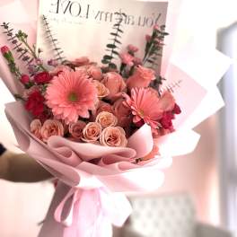 Pink bouquet of roses and gerbera daisies wrapped in pastel paper