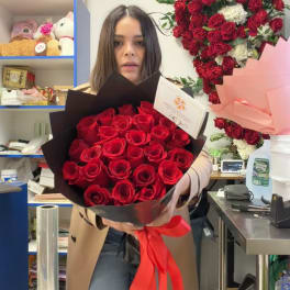 Woman holding a bouquet of red roses wrapped in black paper with a red ribbon