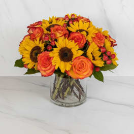 Bouquet of sunflowers and orange roses in a clear glass vase