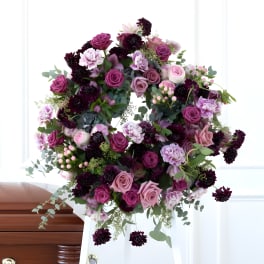 Large purple and pink floral wreath on a white stand