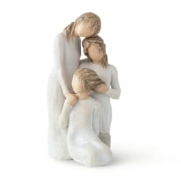 Three faceless figurines in white dresses posed closely together