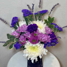 Purple and white chrysanthemum bouquet in a dark vase