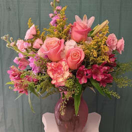 Pink roses and mixed flowers arranged in a purple vase