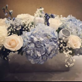 Blue hydrangeas and cream roses arranged in a low box