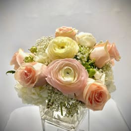 Pastel roses and ranunculus arranged in a clear glass vase