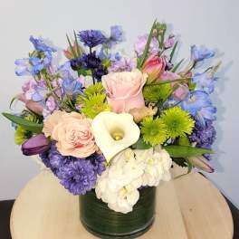Mixed bouquet in a dark green vase with pink, purple, white, and blue flowers