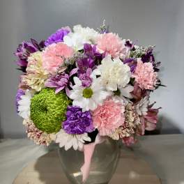 Mixed bouquet of pink, purple, white, and green flowers in a glass vase