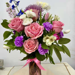 Pink and white mixed bouquet in a pink glass vase with a ribbon