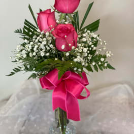 Pink roses in a clear glass vase with a bright ribbon