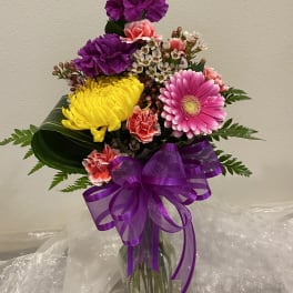 Colorful bouquet of carnations and a pink gerbera daisy in a glass vase