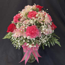 Bouquet of red roses, purple chrysanthemums, and pink carnations in a basket