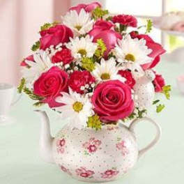 Pink roses and white daisies arranged in a floral teapot